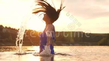 女孩翻着后发。 美丽的水喷在夕阳的光线<strong>中</strong>，水溅在<strong>阳光中</strong>。 她洒了点东西
